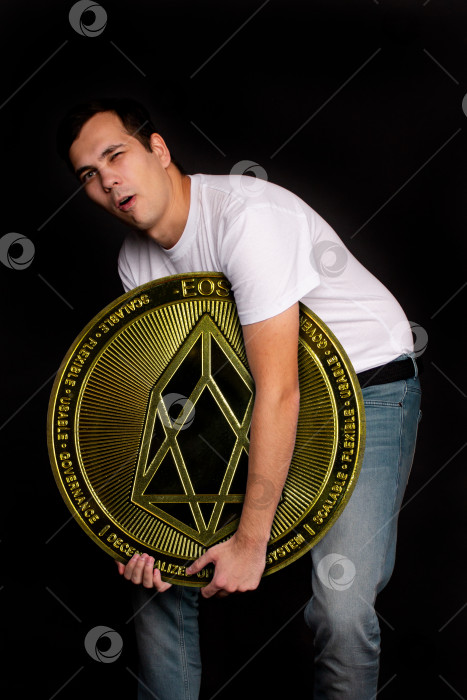 Скачать Молодой парень держит символ монеты eos, современной валюты для обмена и покупок фотосток Ozero