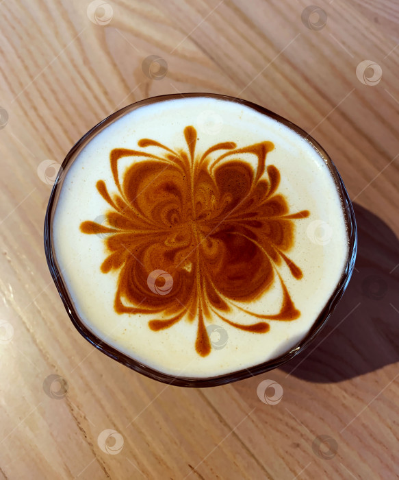 Скачать Чашка кофе с рисунком в виде цветка на сливках. Горячий напиток латте или капучино на столике кафе. Вид сверху. фотосток Ozero