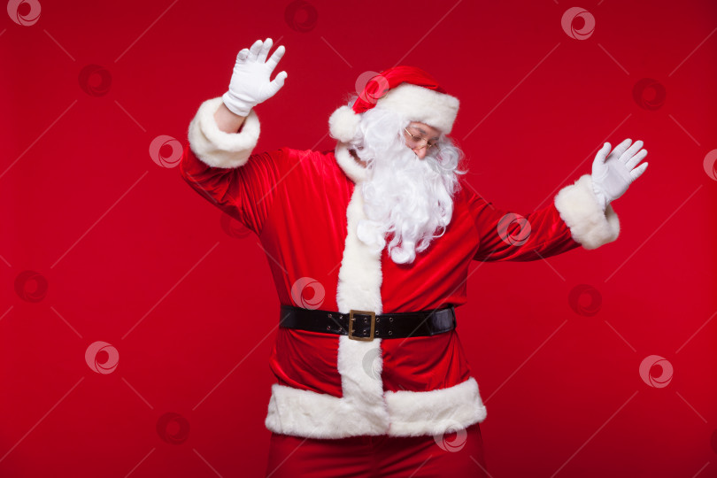 Скачать Санта-Клаус танцует изолированно на красном фоне. фотосток Ozero