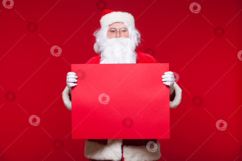 Скачать Санта-Клаус указывает на пустой рекламный баннер, выделенный на красном фоне с пробелом для копирования красного листа фотосток Ozero
