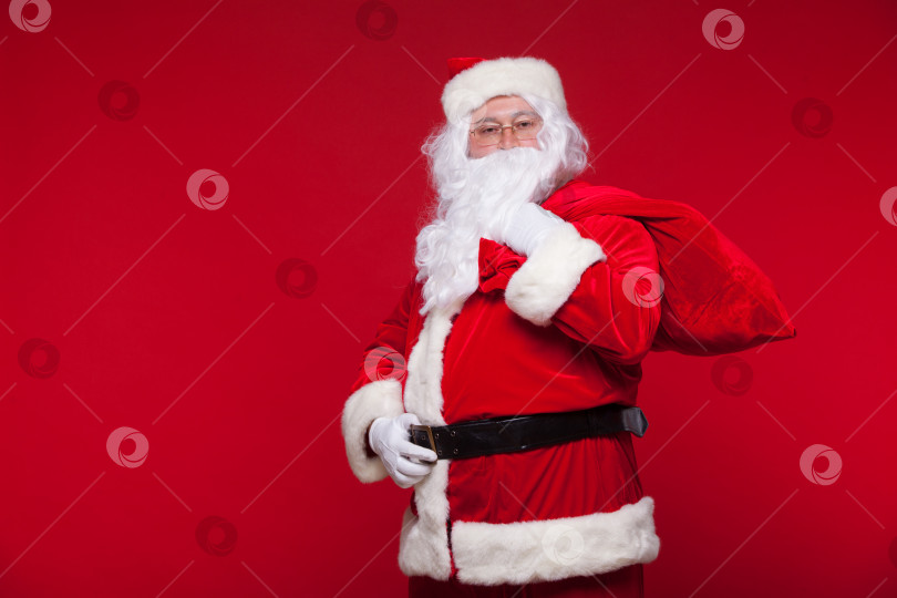 Скачать Рождество. санта-Клаус с большой сумкой на плече на красном фоне фотосток Ozero