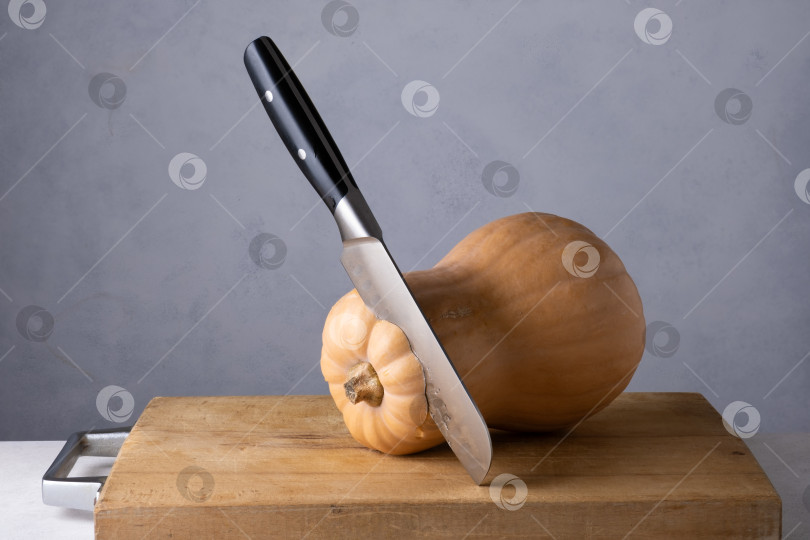 Скачать Спелая тыква и большой кухонный нож на деревянной разделочной доске. фотосток Ozero