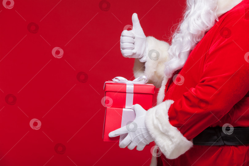 Скачать рождественская фотография руки Санта-Клауса в перчатке с красной подарочной коробкой. большой палец вверх фотосток Ozero