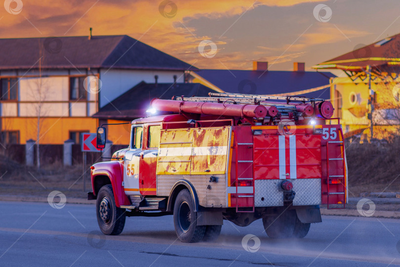 Скачать Череповец, Россия, 08 апреля 2023 года Красная пожарная машина быстро проезжает по городской улице, чтобы потушить пожар. Синий проблесковый маячок сирены на красной машине пожарных, скорой помощи или спасателей. фотосток Ozero