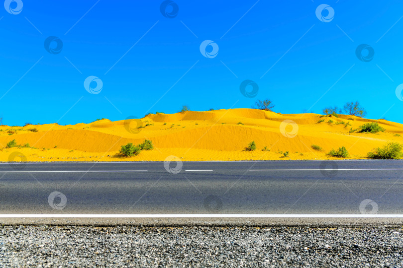 Скачать Песчаные дюны в Астраханской пустыне, Россия. Дорога, шоссе через пустыню в избирательном фокусе. Концепция свободы и путешествий. фотосток Ozero