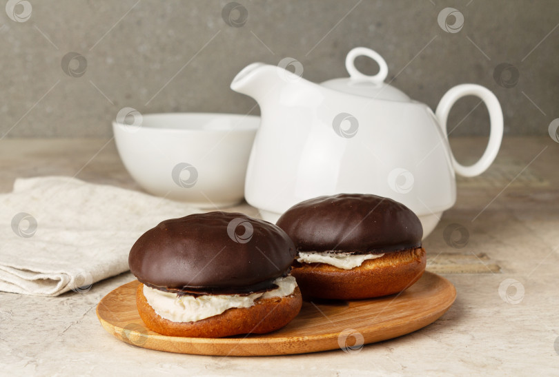 Скачать бисквитные коржи в шоколадной глазури на фоне чайника и чашки, на столе фотосток Ozero