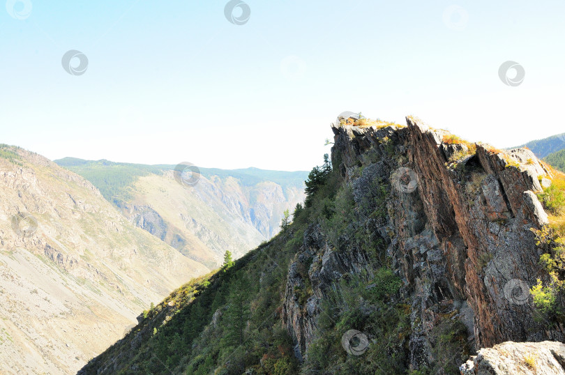 Скачать Гребень высокой скалы со слоистыми скальными образованиями, возвышающийся над глубоким каньоном. фотосток Ozero