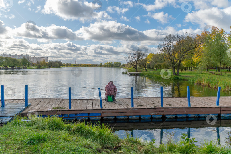 Скачать Рыбак на  берегу городского пруда фотосток Ozero