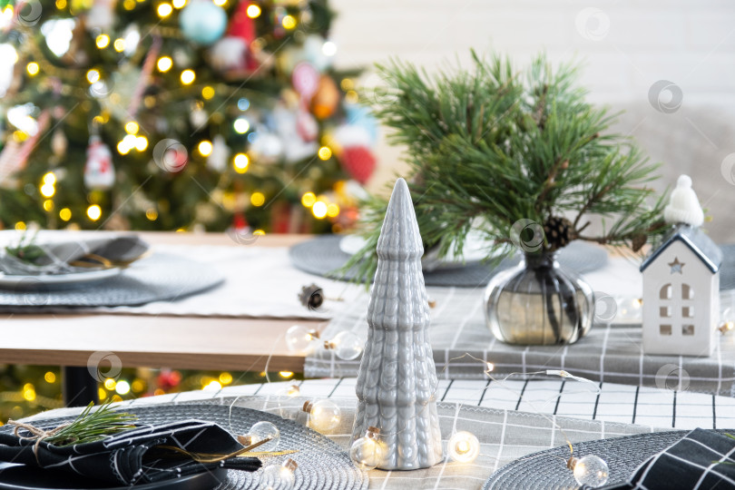 Скачать Сервировка праздничного стола тарелками, вилками, ножами, салфетками, бокалами крупным планом в современном интерьере лофт-дома, украшенного к Рождеству и Новому году. Ждем гостей на праздничный ужин фотосток Ozero