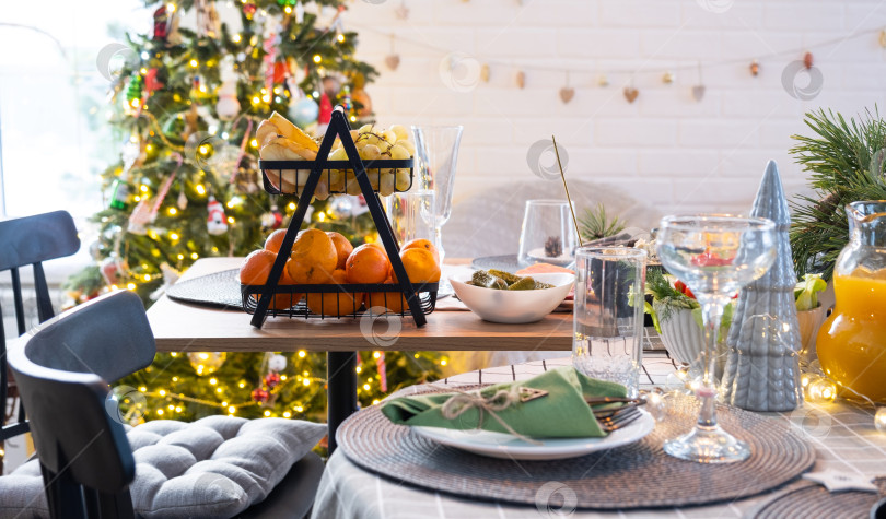 Скачать Сервировка праздничного стола с закусками, салатами и вкусностями крупным планом в современном интерьере лофт-дома, украшенного к Рождеству и Новому году. Ждем гостей на праздничный ужин фотосток Ozero