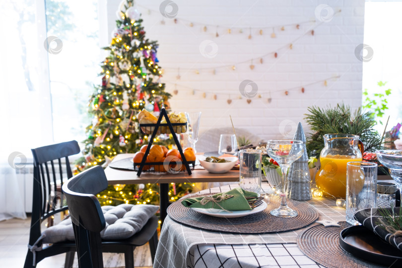 Скачать Праздничный интерьер дома оформлен к Рождеству и Новому году в стиле лофт с черной печью, камином, рождественской елкой. Теплая комната-студия с накрытым столом, горящими дровами, уютом и отоплением дома фотосток Ozero
