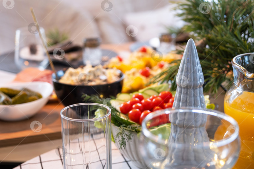 Скачать Сервировка праздничного стола с закусками, салатами и вкусностями крупным планом в современном интерьере лофт-дома, украшенного к Рождеству и Новому году. Ждем гостей на праздничный ужин фотосток Ozero