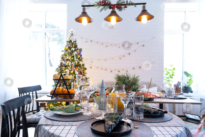 Скачать Праздничный интерьер дома оформлен к Рождеству и Новому году в стиле лофт с черной печью, камином, рождественской елкой. Теплая комната-студия с накрытым столом, горящими дровами, уютом и отоплением дома фотосток Ozero