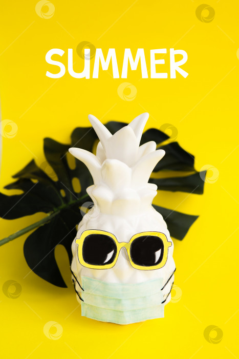 Скачать Ананас в медицинской маске и солнцезащитных очках на желтом фоне. Лето во время Covid-19. Видение на лето 2020 года во время пандемии коронавируса. фотосток Ozero