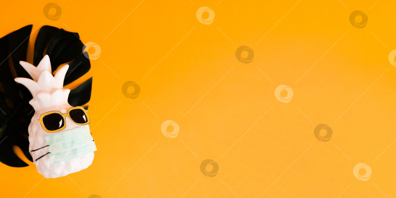 Скачать Ананас в медицинской маске и солнцезащитных очках на оранжевом фоне. Летняя концепция. Видение на лето 2020 года во время пандемии коронавируса. фотосток Ozero