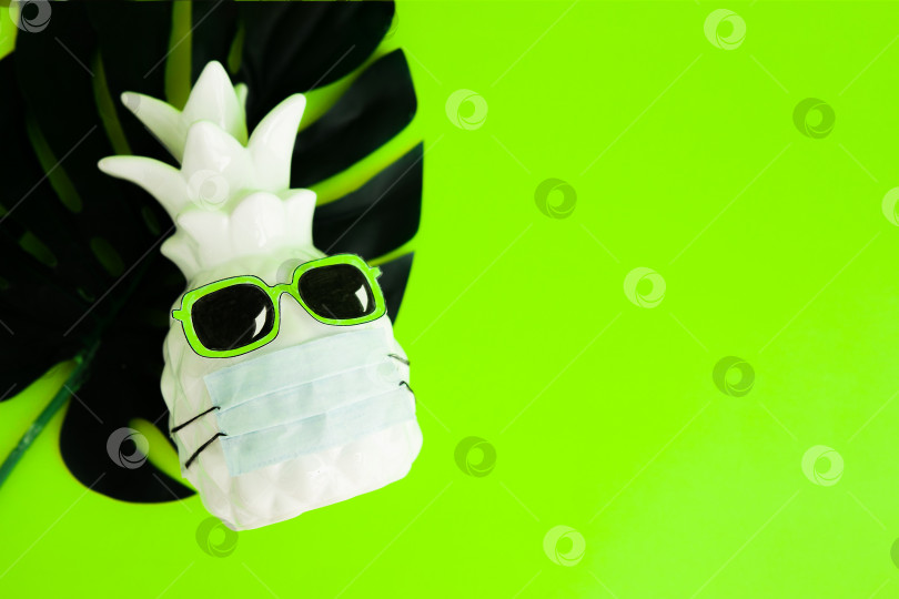 Скачать Ананас в медицинской маске и солнцезащитных очках на зеленом неоновом фоне. Летняя концепция. Лето во время Covid-19. Видение на лето 2020 года во время пандемии коронавируса. фотосток Ozero