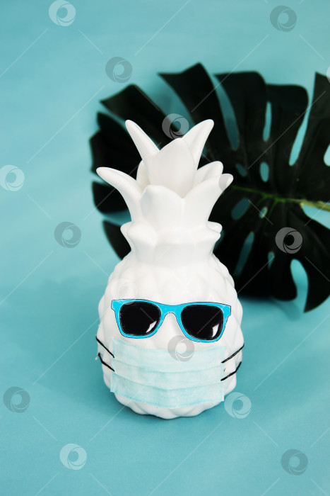 Скачать Ананас в медицинской маске и солнцезащитных очках на синем фоне. Летняя концепция. Видение на лето 2020 года во время пандемии коронавируса. фотосток Ozero