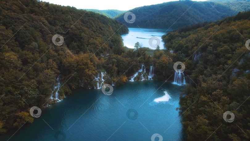 Скачать Золотой осенний лес и горное озеро с удивительными водопадами. Прозрачная изумрудно-зеленая вода. Солнечная погода быстро сменяется темной. фотосток Ozero