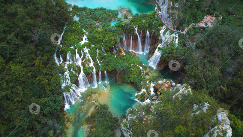 Скачать Туристы посещают знаменитые Плитвицкие водопады в Хорватии. Горные ручьи впадают в озеро с лазурно-прозрачной водой. Летний национальный парк. фотосток Ozero