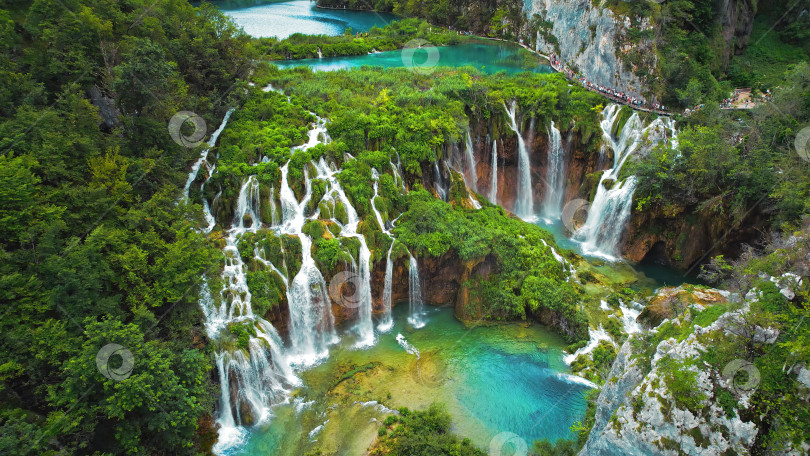 Скачать Толпы туристов посещают знаменитые Плитвицкие водопады в Хорватии. Летний пейзаж. Горные ручьи впадают в озеро с лазурно-прозрачной водой. фотосток Ozero