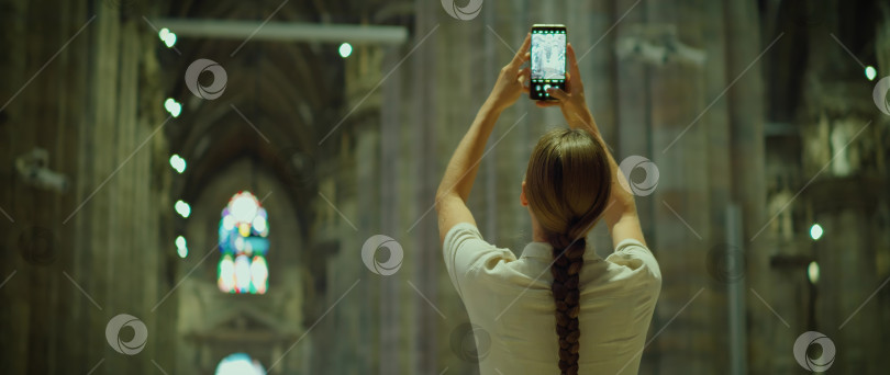 Скачать Женщина фотографирует на свой телефон во время обзорной экскурсии по городу в Италии. Архитектура старинного здания. Турист фотографирует. фотосток Ozero