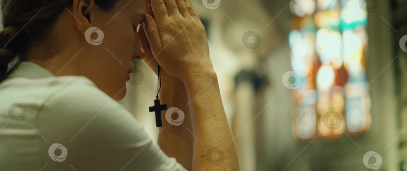 Скачать Взрослая девушка преклонила колени в благодарственной молитве Богу в кафедральном соборе. Лицо искренне верующей женщины крупным планом. фотосток Ozero