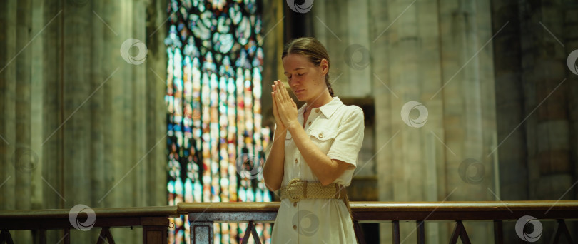 Скачать Молодая женщина молится в церкви. Религиозная взрослая девушка обращается к Богу в молитве. фотосток Ozero