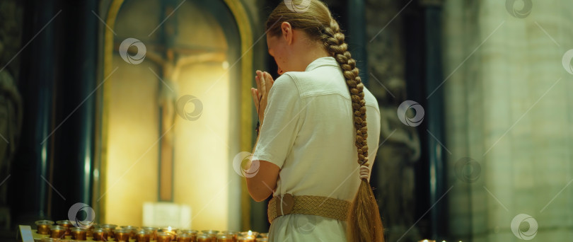 Скачать Женщина молится в кафедральном соборе. Распятие Иисуса Христа и горящие свечи на заднем плане. фотосток Ozero