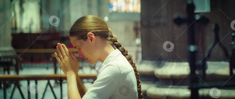 Скачать Женщина молится в церкви. Размытый фон с молодой религиозной взрослой девушкой, опустившейся на колени в молитве к Богу. фотосток Ozero