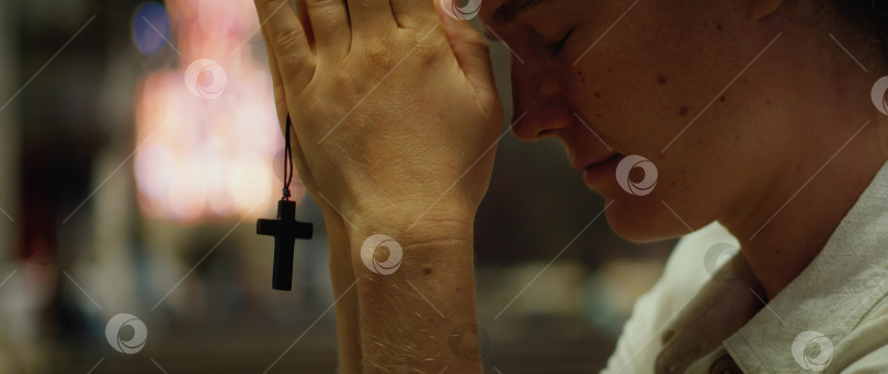 Скачать Женщина держит в руках религиозный крест и молится в храме. фотосток Ozero