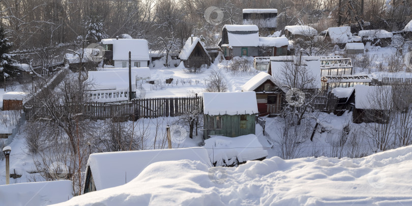 Скачать Обшарпанные неприхотливые загородные домики зимой. Все покрыто снегом. Светит солнце. Следы ведут к дачному поселку. фотосток Ozero