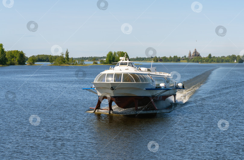 Скачать Туристический теплоход на подводных крыльях "Метеор", плывущий по Онежскому озеру на фоне исторического парка "Кижи" фотосток Ozero