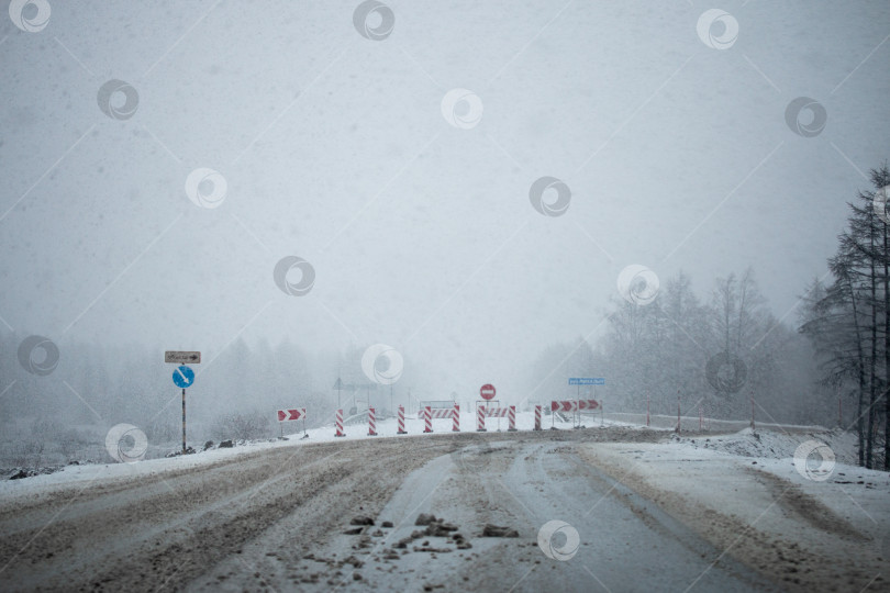 Скачать Дорожные знаки объезда, занесенные снегом во время снегопада в Магадане, Россия фотосток Ozero