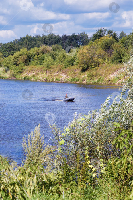 Скачать Рыбак в лодке плывет по реке. фотосток Ozero