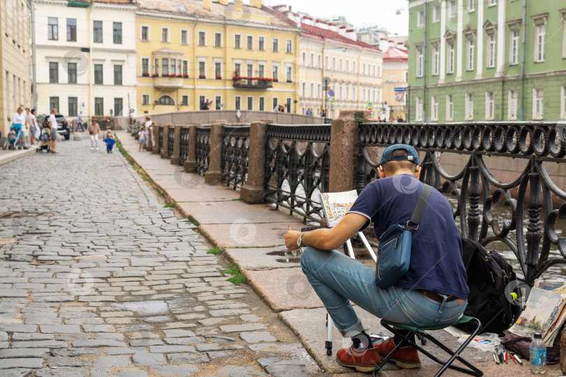 Скачать художник рисует городской пейзаж, сидя на набережной фотосток Ozero