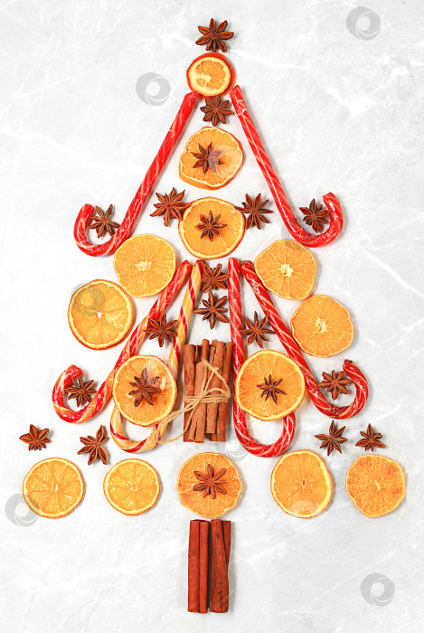 Скачать Рождественский фон в виде съедобной рождественской елки с традиционными зимними специями для повышения иммунитета в холодный период. Звездчатый анис, корица и сушеные апельсины и мандарины на темном фоне. Канун Нового года фотосток Ozero