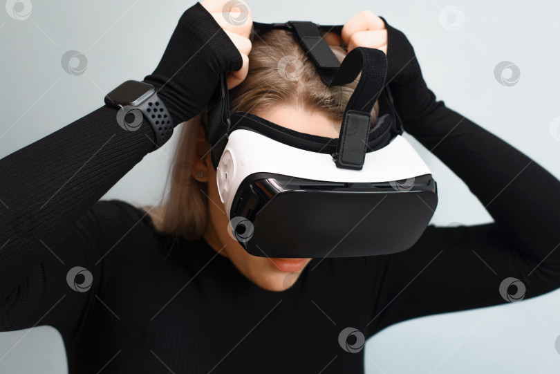 Скачать Молодая женщина надевает очки виртуальной реальности, VR. Девушка, использующая интерактивное устройство, в помещении. Новые технологии, оборудование для концепции игрового моделирования. фотосток Ozero