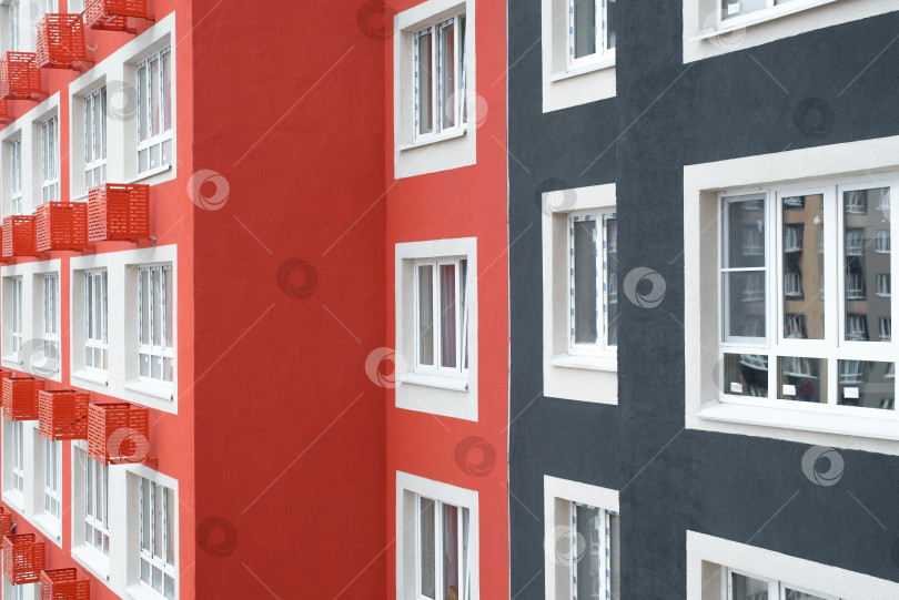 Скачать Фасад многоэтажного жилого дома, внешний вид крупным планом. Разноцветная отделка стен и пластиковые окна снаружи. фотосток Ozero