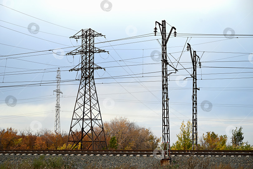 Скачать Высоковольтные линии электропередачи, проходящие через вспаханное поле, на фоне красивого облачного неба. фотосток Ozero