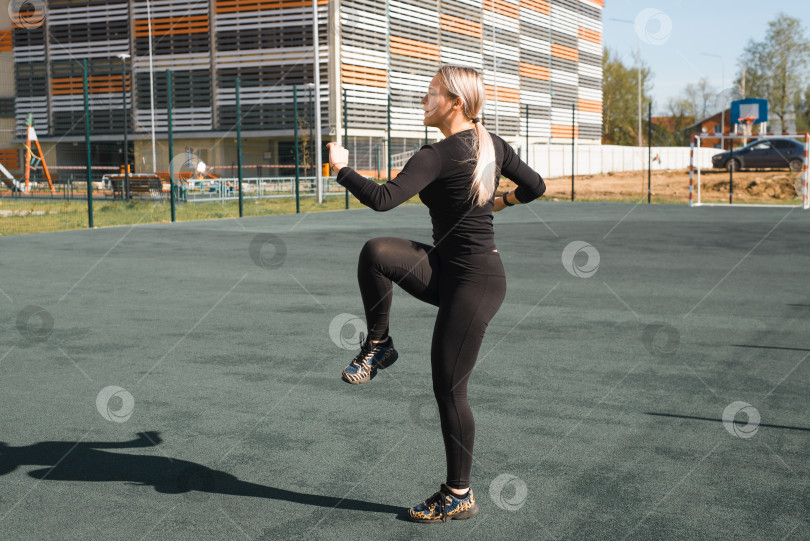 Скачать Уличные тренировки, здоровый активный образ жизни. Фитнес-молодая женщина разминается перед тренировкой на открытом воздухе. Спортсменка в черном обтягивающем спортивном костюме тренируется на детской площадке. фотосток Ozero
