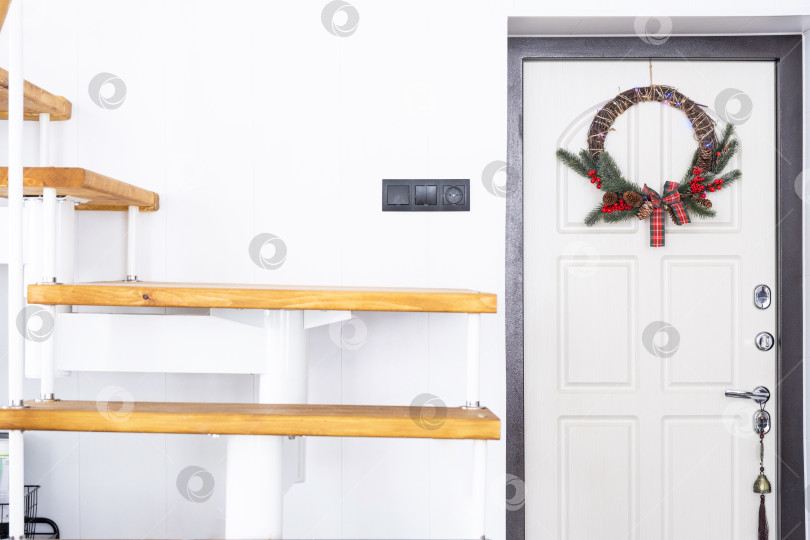 Скачать Входная дверь в прихожей дома с рождественским венком. Металлическая модульная лестница на второй этаж. фотосток Ozero