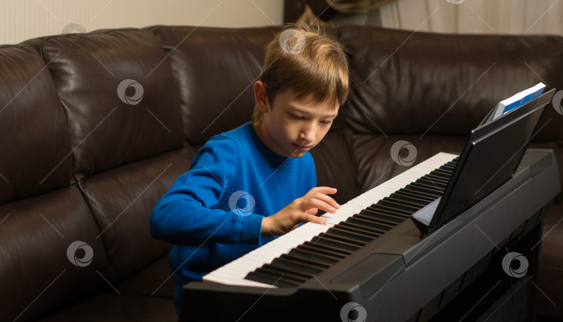 Скачать Сосредоточенный мальчик, играющий на пианино фотосток Ozero