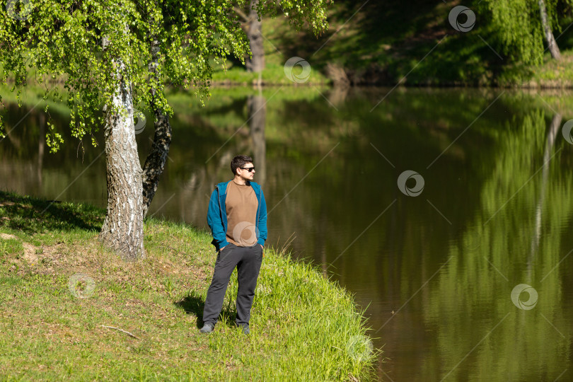 Скачать Мужчина в темных очках стоит на берегу озера фотосток Ozero