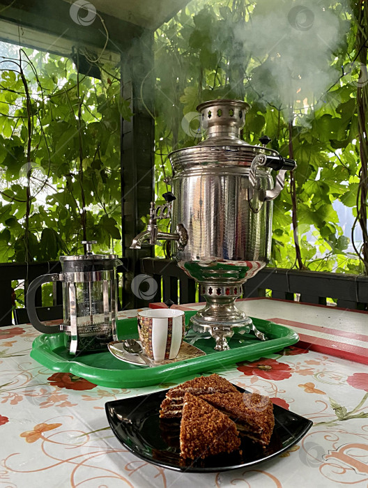 Скачать Самовар, чашки и торт на фоне зелени фотосток Ozero