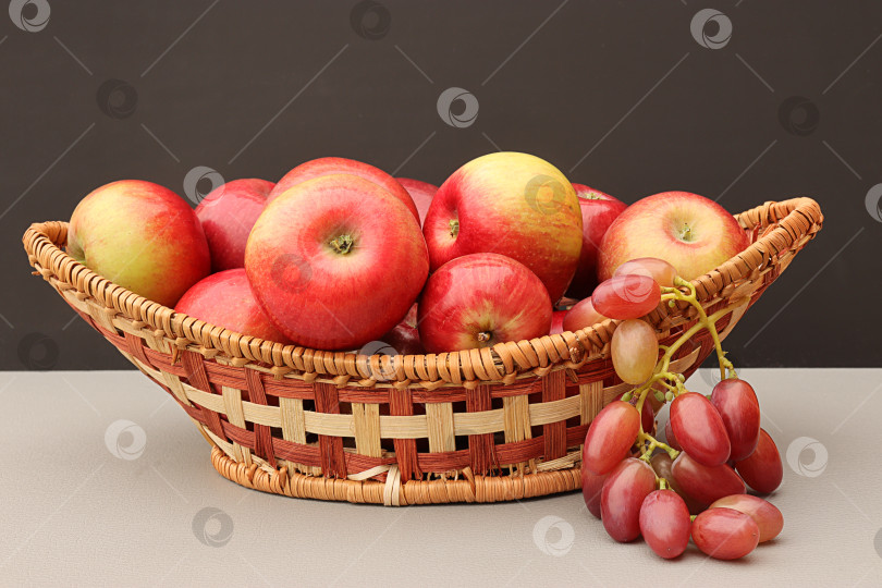 Скачать яблоки и виноград в плетеной деревянной корзине на столе фотосток Ozero
