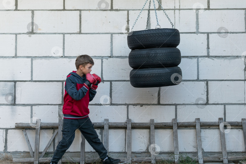 Скачать Маленький мальчик в боксерских перчатках бьет по самодельной груше фотосток Ozero