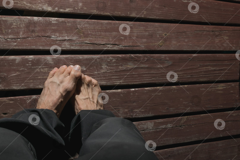 Скачать Ноги взрослого мужчины на деревянной платформе фотосток Ozero