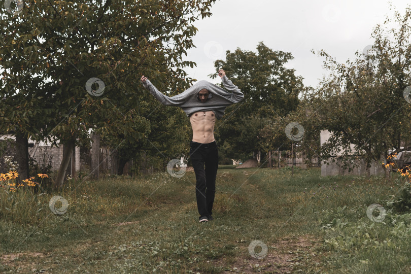 Скачать Молодой парень снимает с себя одежду во время прогулки фотосток Ozero