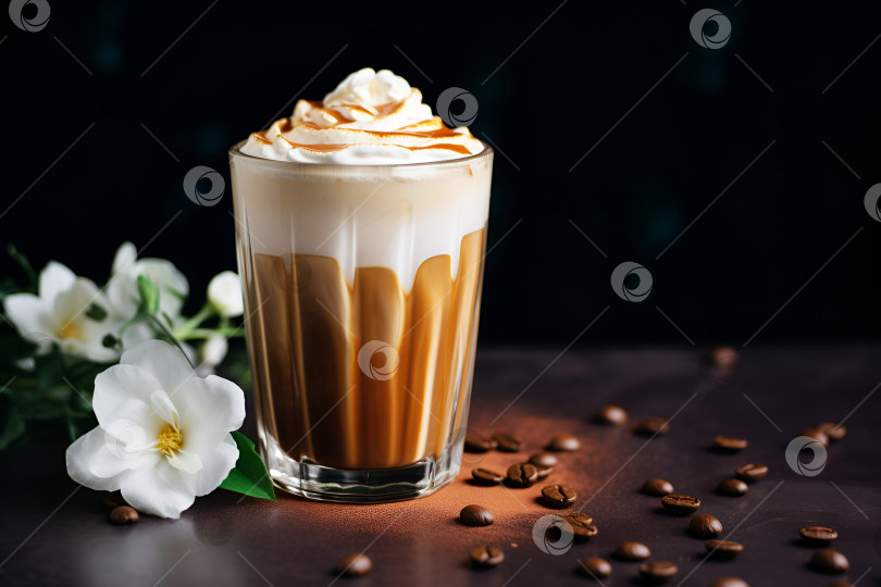 Скачать Бокал кофе "Далгона" со взбитыми сливками и карамелью на темном фоне с белыми цветами, модный кофейный напиток. Кофейный латте готовится из взбитой пены растворимого кофе и заливается молоком фотосток Ozero