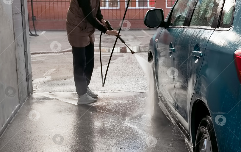 Скачать Ручная мойка автомобиля водой под давлением на автомойке снаружи. Летняя мойка автомобиля. Чистка автомобиля водой под высоким давлением. Мытье с мылом. Концепция крупным планом. фотосток Ozero